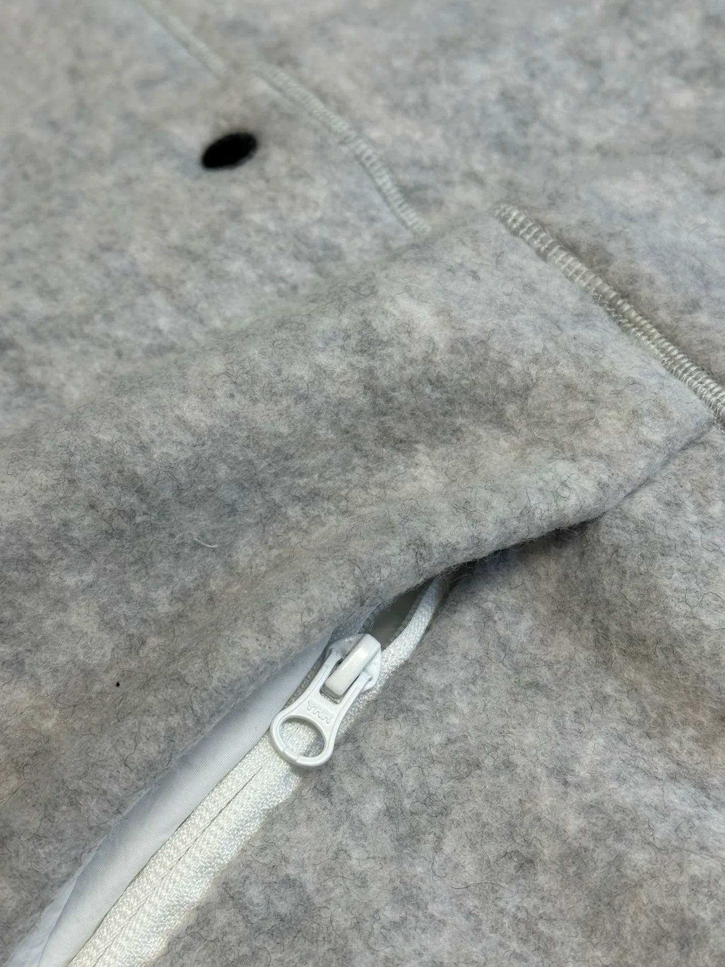 P770 Canada Goose Fleece Badge Button Jacket The main fabric of this jacket is light gray wool blend fabric to improve the fabric's wear resistance, wrinkle resistance and warmth. Wool provides good warmth and a natural feel, while blended fibers enhance the fabric's practicality and durability.  The cutting process needs to ensure that the texture and color of the fabric are evenly distributed, especially with this light gray tone, to avoid chromatic aberrations. The stretchability of wool-blend fabrics needs to be taken into consideration when cutting pieces to ensure dimensional stability of the finished garment.  Use a sewing needle and thread suitable for wool-blend fabrics to avoid damage to the fabric during sewing. The sewing stitches are even and firm to prevent thread stripping.  The temperature needs to be controlled during ironing to avoid high temperature damage to the fabric while keeping the fabric smooth and crisp. The front and back body parts, sleeves and other main parts are stitched with flat seams to ensure a smooth silhouette. Align the fabric texture at the splices to keep the look neat.  The white circular armband on the left arm is an important part of the brand identity and is finely sewn to ensure it is strong and flat.  size：s m l xl